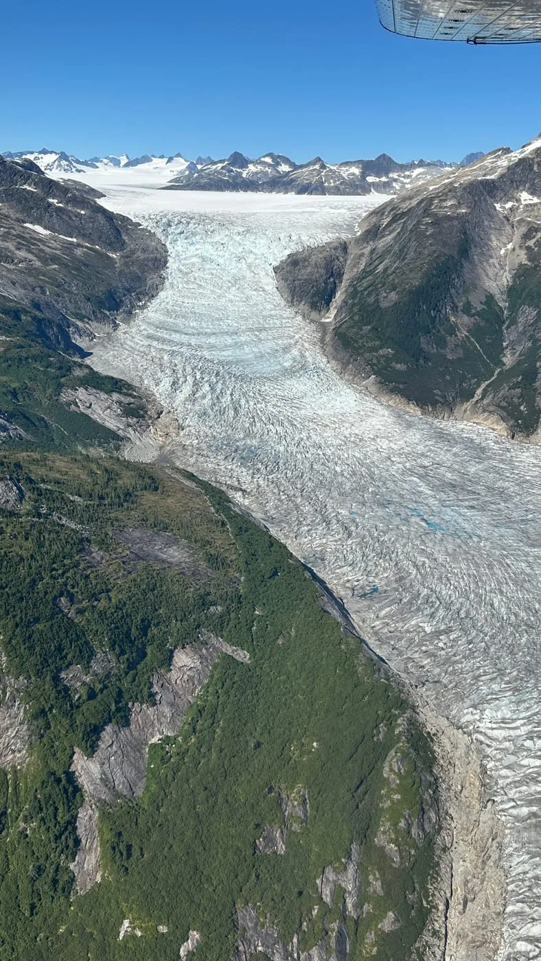 A glacier winding down a mountain valley, seen from the air