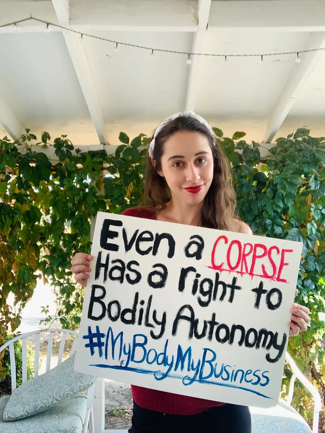 Erica holding a sign: Even a corpse has a right to bodily autonomy. #MyBodyMyBusiness